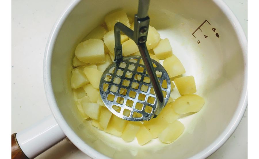 茹でたジャガイモをマッシュしている