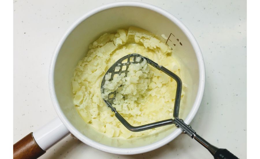 茹でたジャガイモをマッシュしている