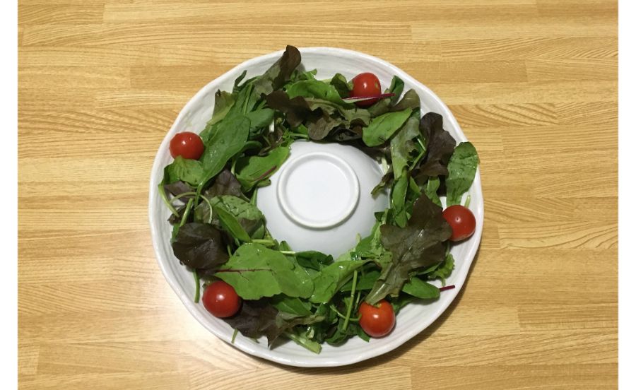 丸いお皿のうえにリーフサラダを盛っている