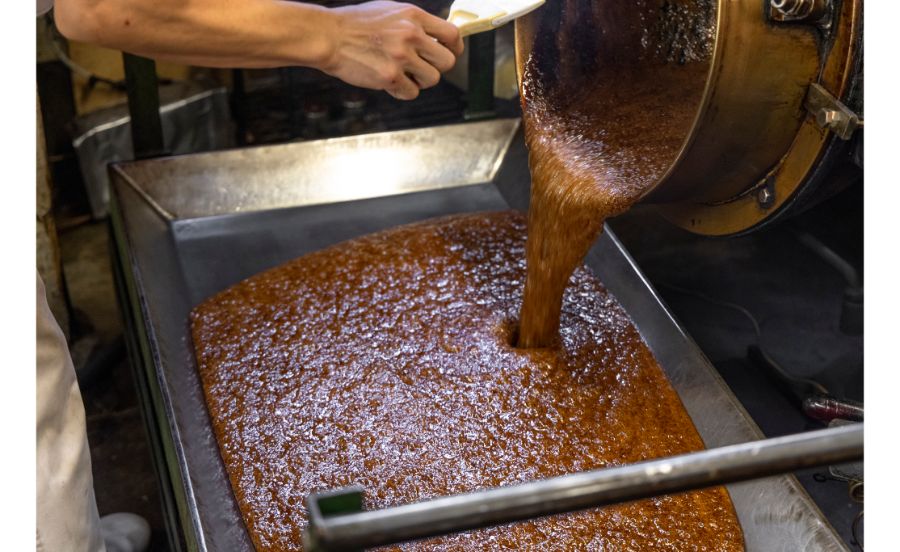 炊いた飴を冷却台に流し込む作業