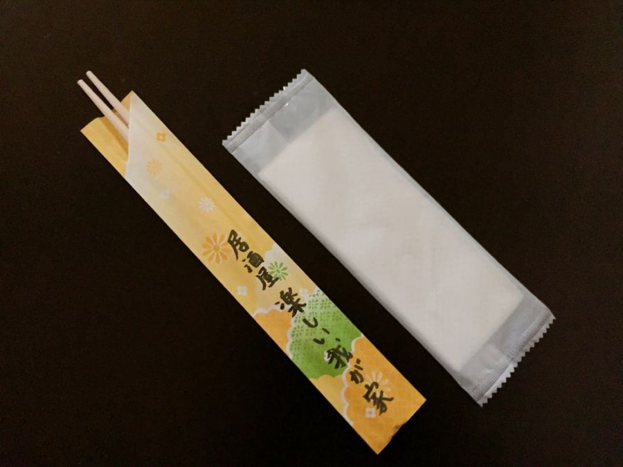 おしぼりと使い捨ての箸。箸袋には「居酒屋　楽しい我が家」の文字