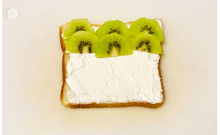 生クリームをぬった食パンにキウイをのせている
