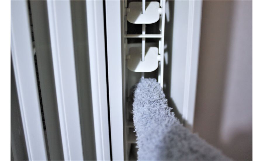 窓用エアコンの羽につもったホコリを掃除しているところ