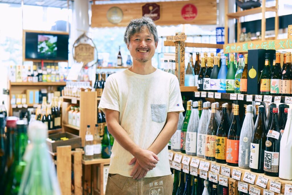 酒が陳列された店内で笑顔のオーナー藤本さん