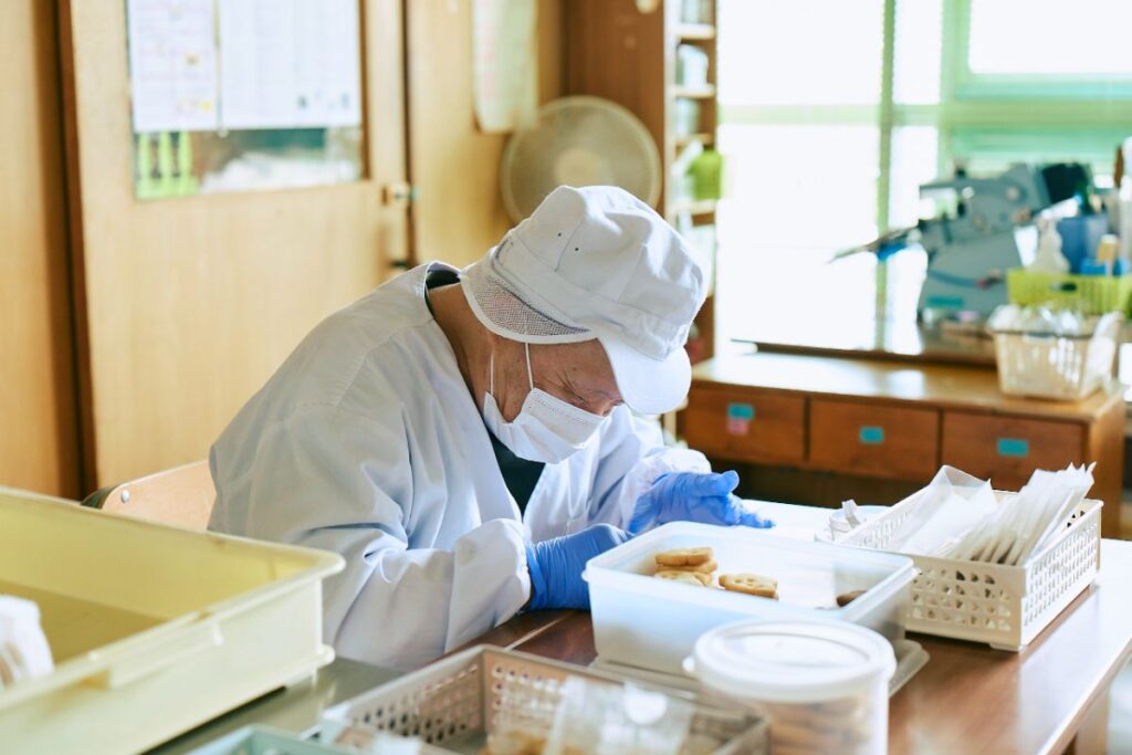 クッキーを丁寧に作る作業所の人