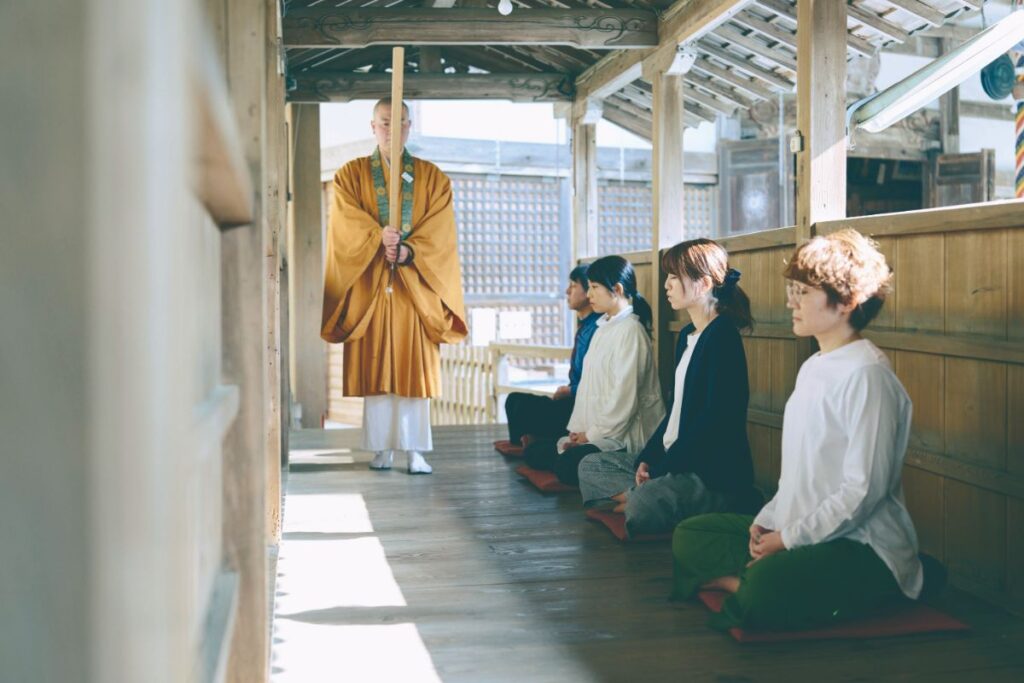 お寺の廊下で座禅を組む人々