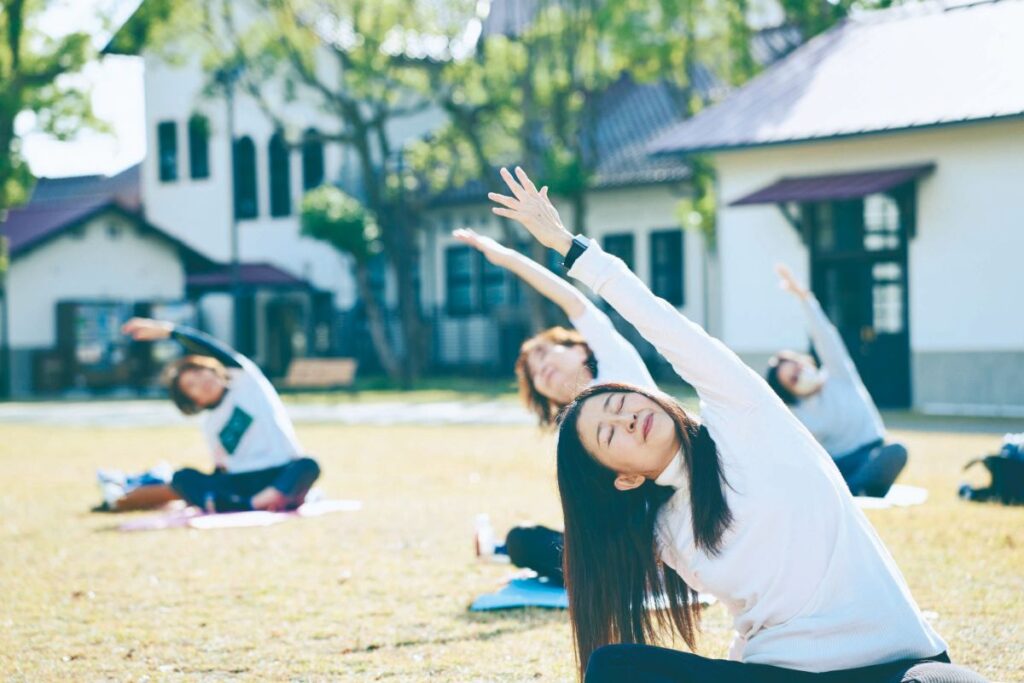 気持ちよさそうに腕を空に伸ばして屋外でヨガをする女性