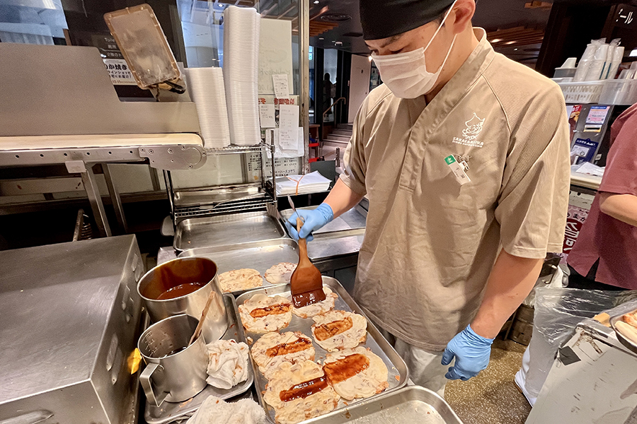 阪神名物いか焼きでイカ焼きにソースを塗る